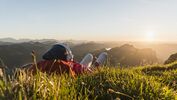 Hiker lying in grass, taking a break and listening music with headphones