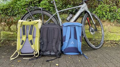 Radtaschen-Rucksack-Hybride von Deuter, Vaude und Thule in der Vergleichsansicht neben Fahrrad